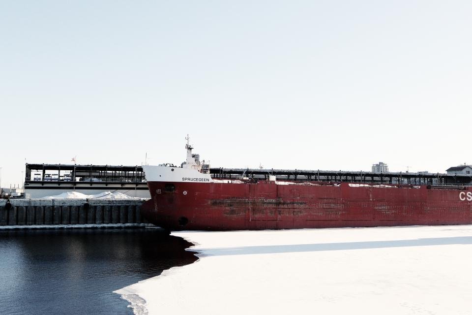 A red cargo ship moored at a harbour